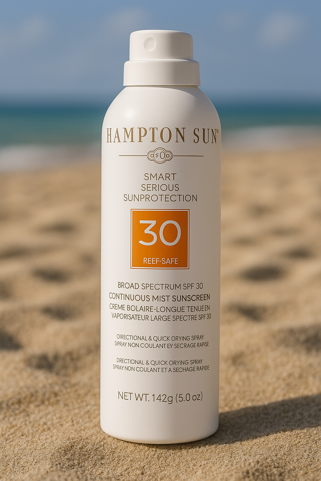 White aerosol can of Hampton Sun Smart Serious Sun Protection spray with SPF 30, labeled reef-safe and continuous mist, standing on sand with a blurred beach and ocean in the background.