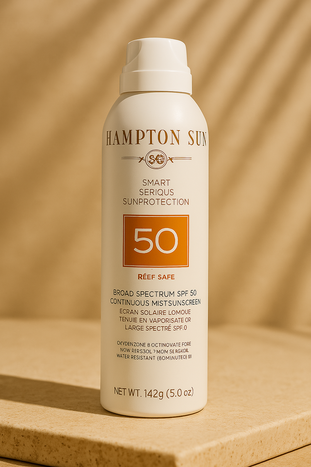 Hampton Sun SPF 50 continuous mist sunscreen in a white spray bottle with an orange label and reef-safe tag, displayed on a stone-textured platform under warm lighting.