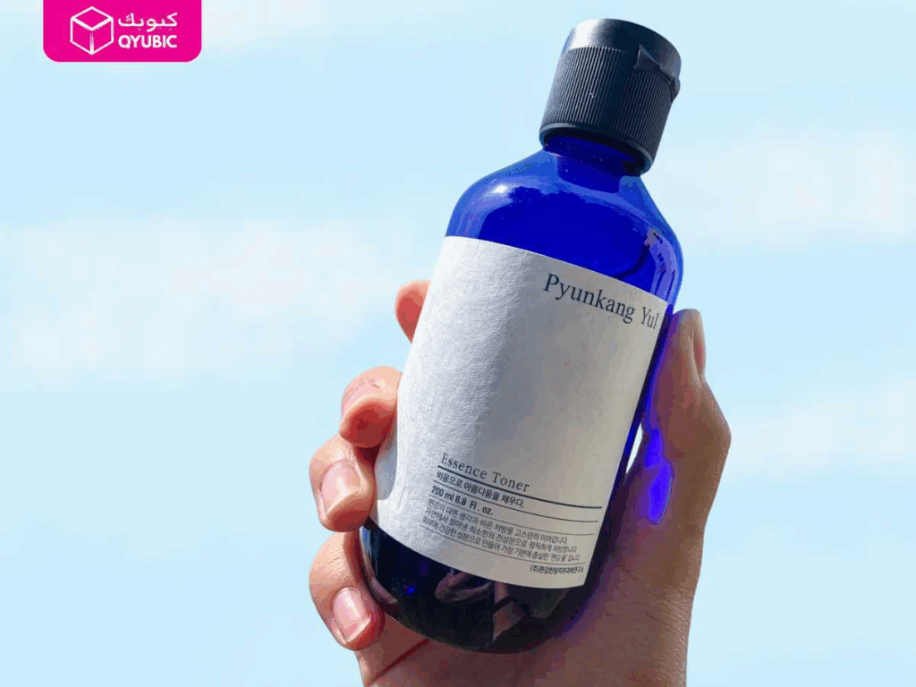 A hand holding the iconic Pyunkang Yul Essence Toner against a clear blue sky, one of the best Korean beauty products in UAE known for its minimal ingredients and deep hydration for sensitive skin